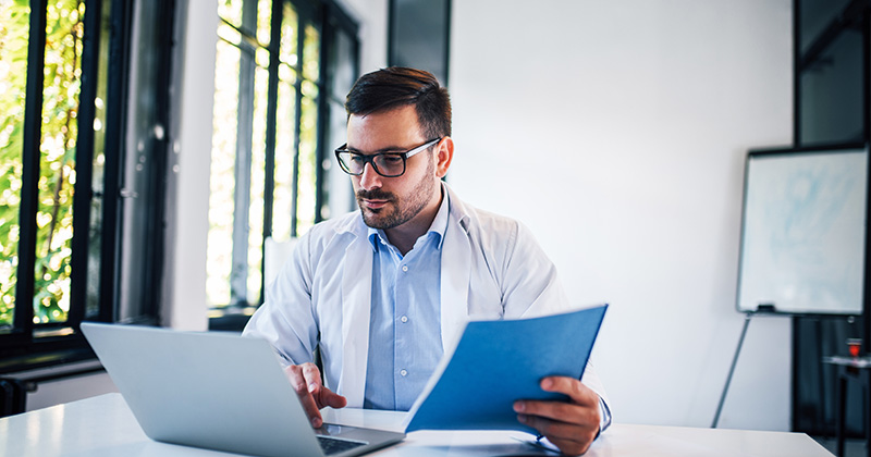 DOCTOR AT LAPTOP WITH FOLDER