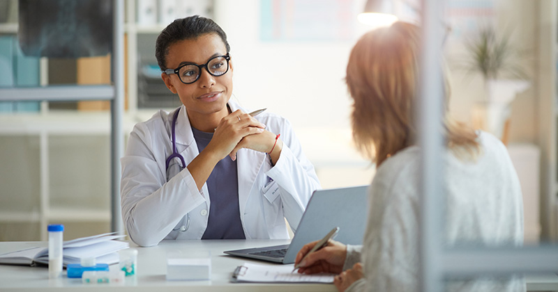 DOCTOR WITH GLASSES TALKING TO REDHEAD PATIENT